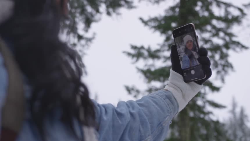 A woman using a cell phone while in a forest