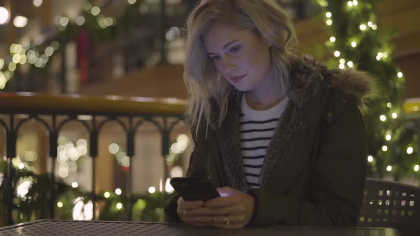 Woman sitting at table typing on her smartphone