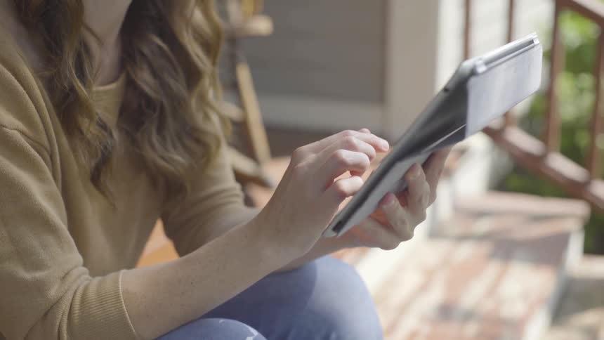 A woman is sitting on the steps using her tablet