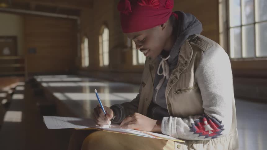 Woman smiles while writing on a notepad