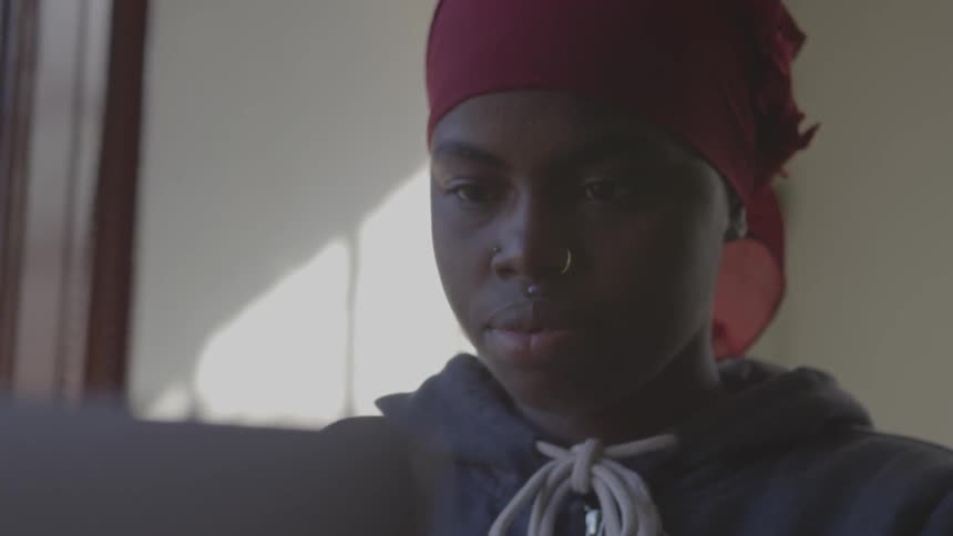 Black girl uses laptop and smiles in room during daylight