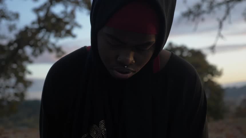 A young black boy looks down