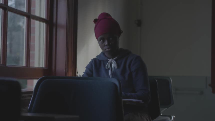 Woman sits in darkened classroom glaring