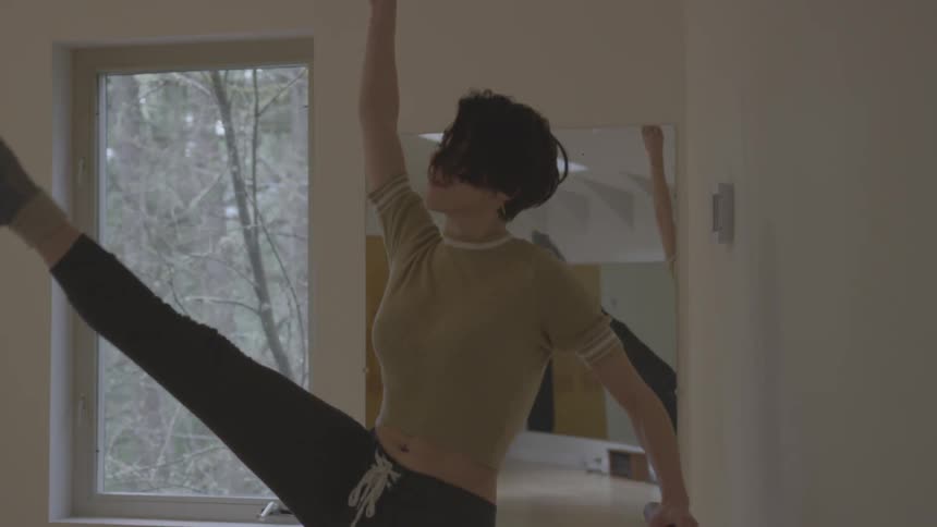 A young woman performs dance moves while holding a banister