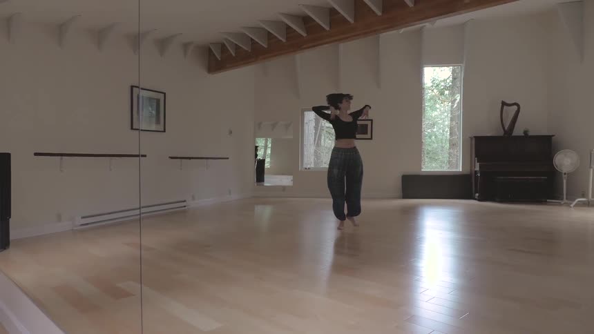 A woman dances in a white walled studio