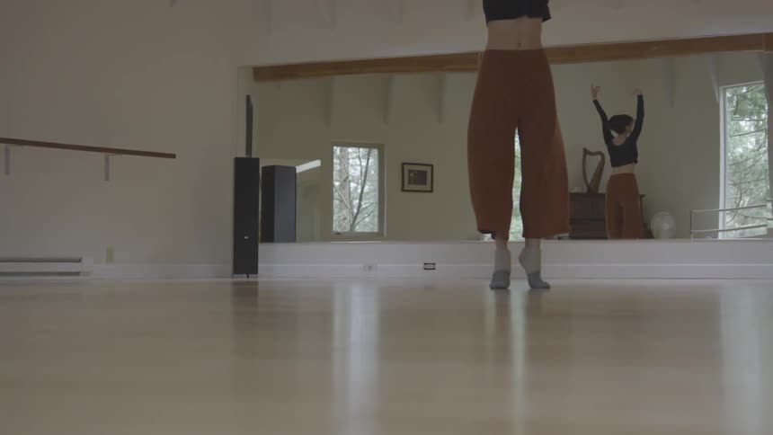 Dancer turns across the floor in front of a mirror in a dance studio
