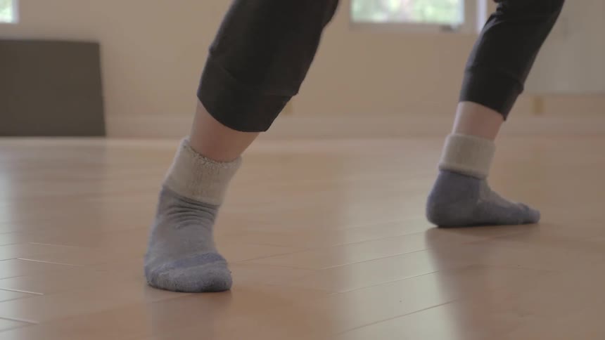 A woman in cotton socks performs stretches in a dance studio