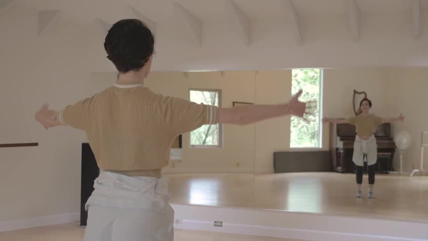 Female dancer is warming up in front of the mirror