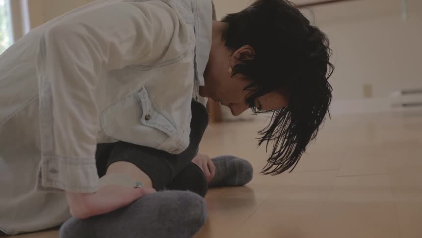A woman sitting crossed legged on the floor while stretching