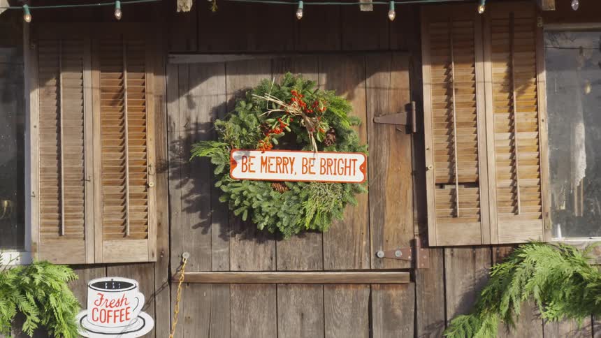 A holiday wreath is hanging on store door