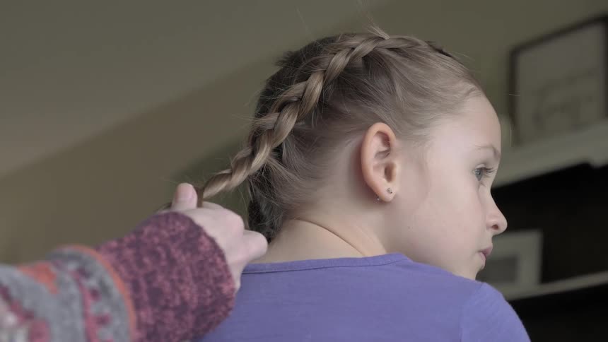 A child is having her hair braided