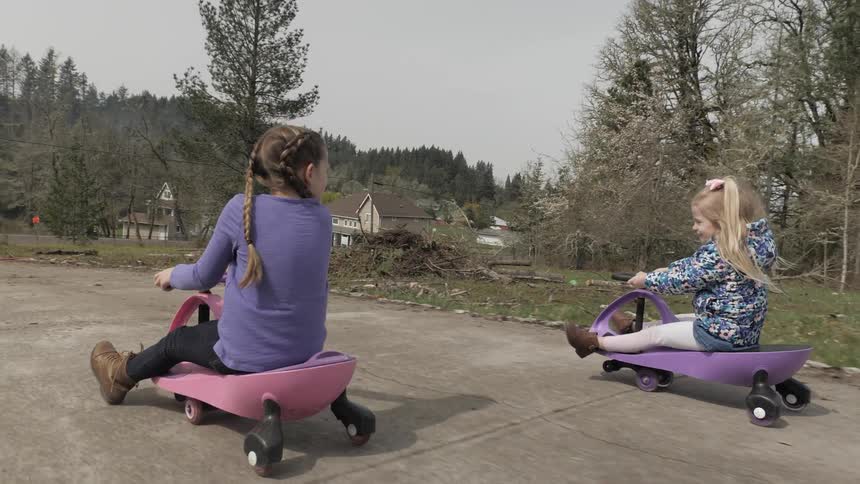 Two children ride carts down a road