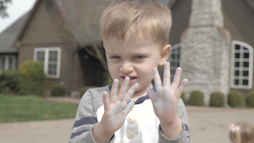 A young boy shows his chalk hands