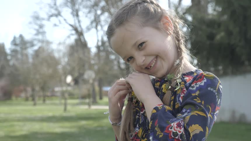 A young girl smiles while playing with her hair