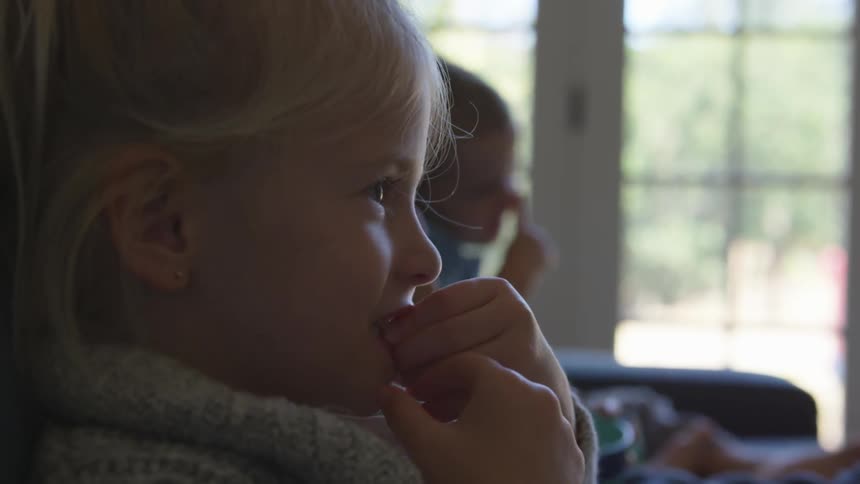 Kids eating snacks on a couch while watching something off screen
