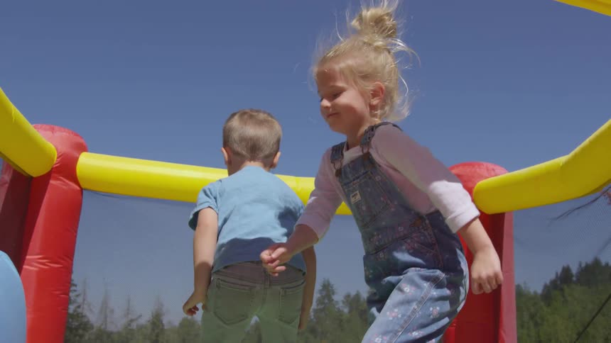 Boy and girl jumping on a bouncy castle on a sunny day