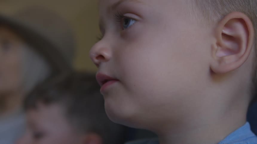 A little boy eats popcorn