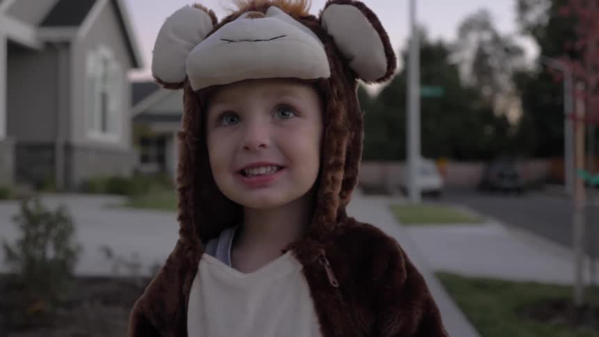A small child standing outside wearing a furry monkey costume