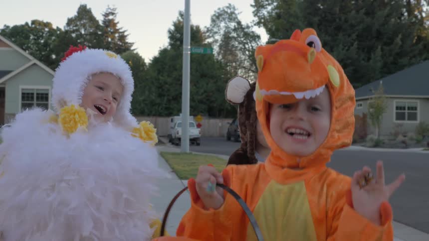 Children walk down the sidewalk in halloween costumes