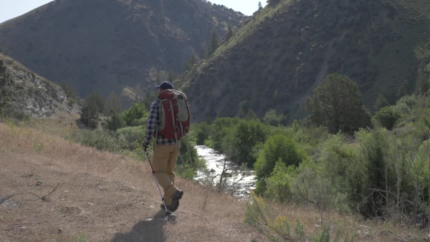 A man walking on a woodland trail near hills