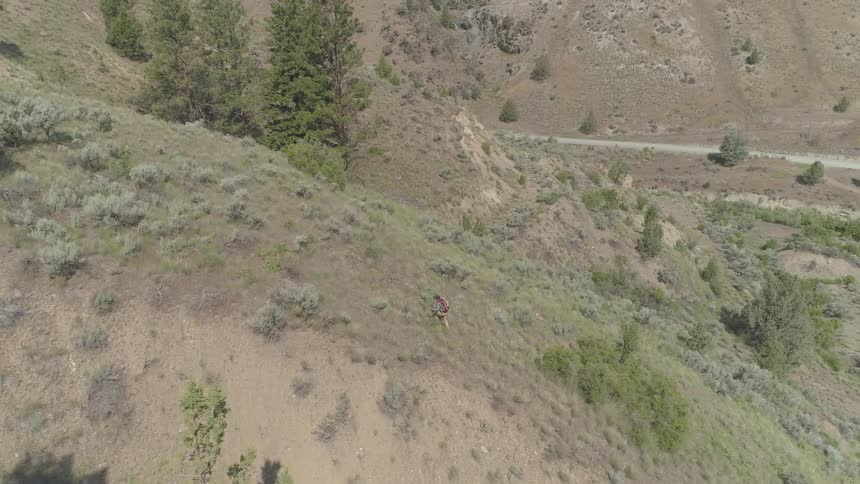 A hiker climbing a large hill during the day