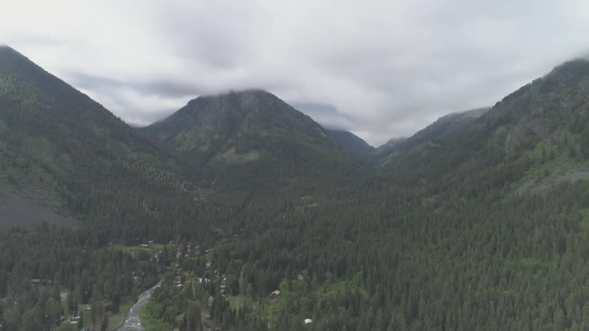 Landscape of mountain forest valley with small village on a cloudy day