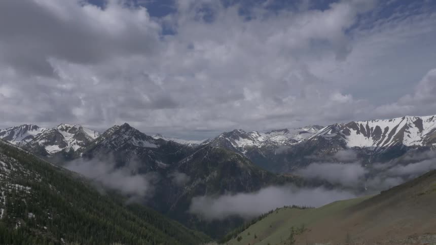 Clouds move over snow covered mountains