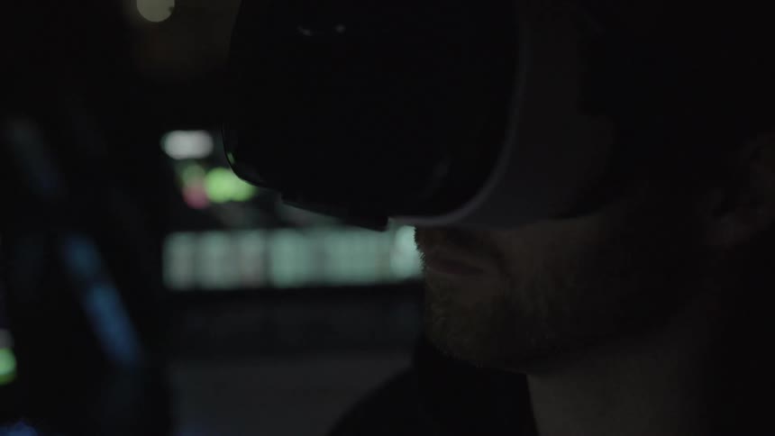 Man wear virtual reality goggles in dark room