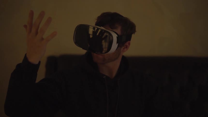 A man wearing vr goggles is moving his hand