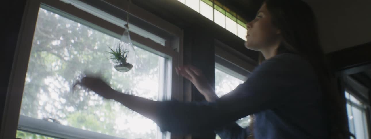 A woman grabs her purse off a chair and shuts a window