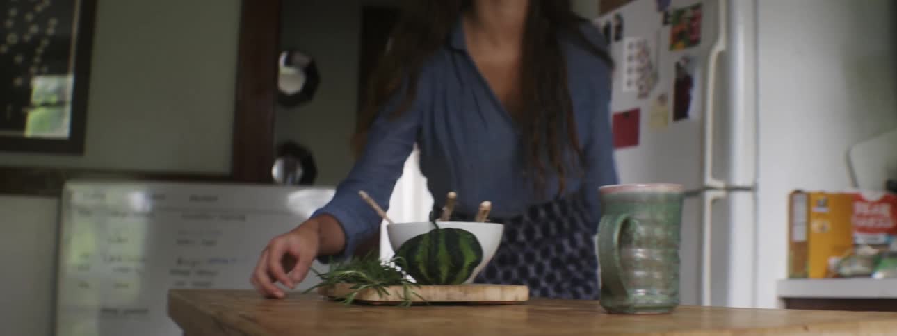 Woman throwing something onto a cutting board and grabbing a mug
