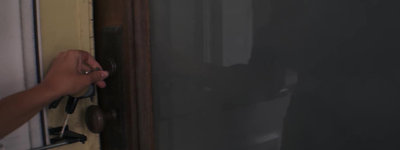 A woman closes a door and locks it with a key on her way out