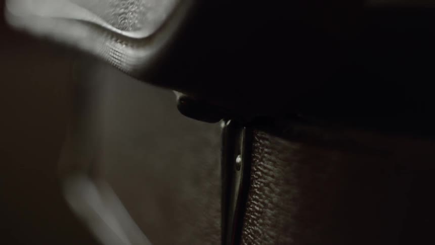 Brown suitcase is being open in a dark room