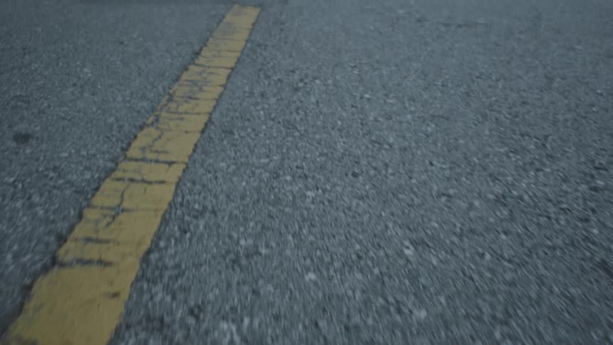 The camera looks down as it moves along a road