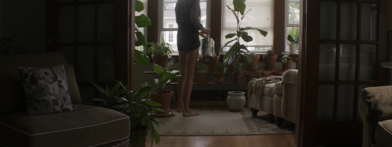 A woman watering plants in a front room