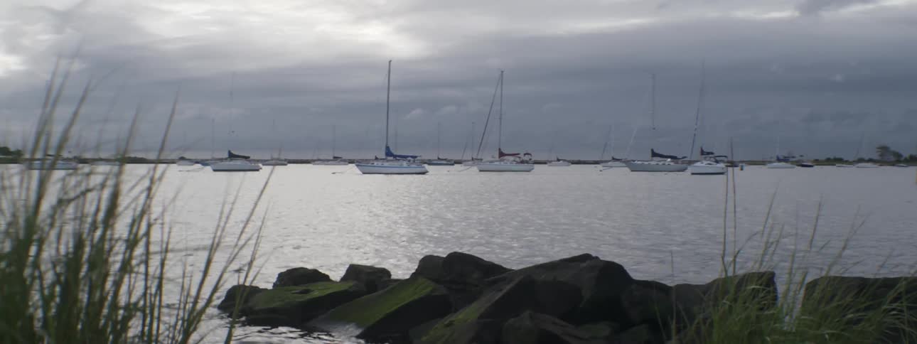 Sailboats anchored under a cloudy sky