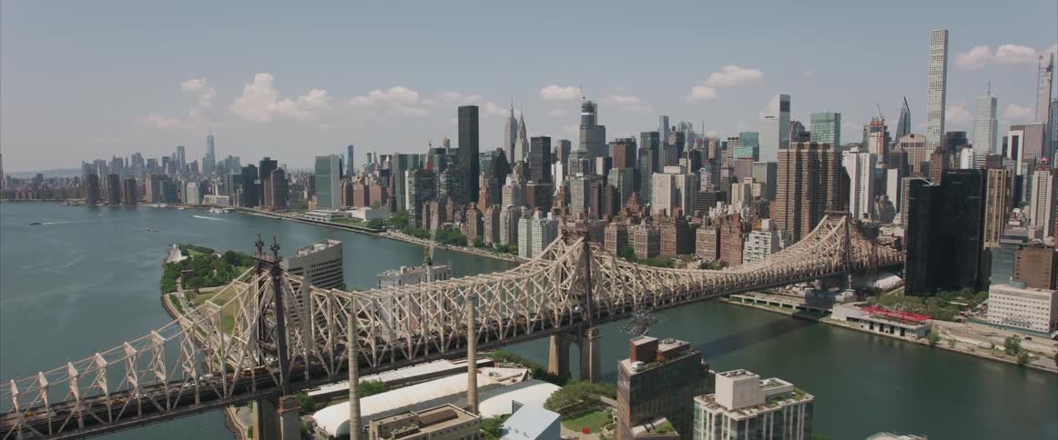 The camera flies over a river next to a dense city