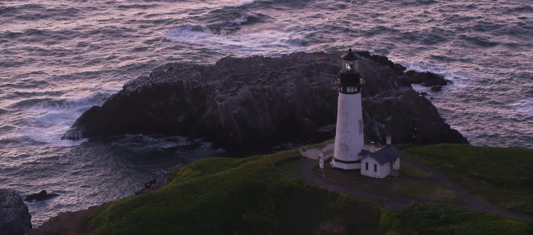 The camera looks down on a lighthouse next to an island