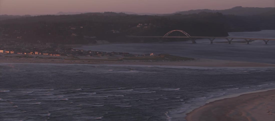 A shoreline with a bridge in the background