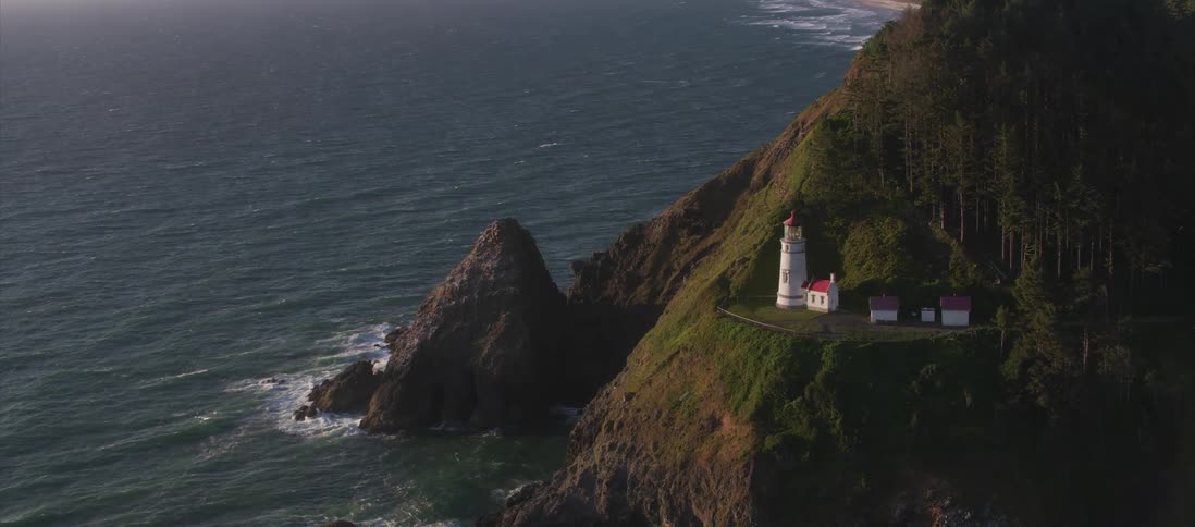 Houses and lighthouse towers are spread along the coast next to the ocean