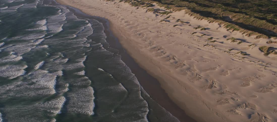 Aerial view of calm sea waves crashing in the sands of a beach