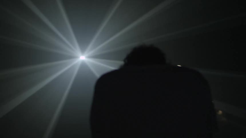 A strobing light shines behind a man