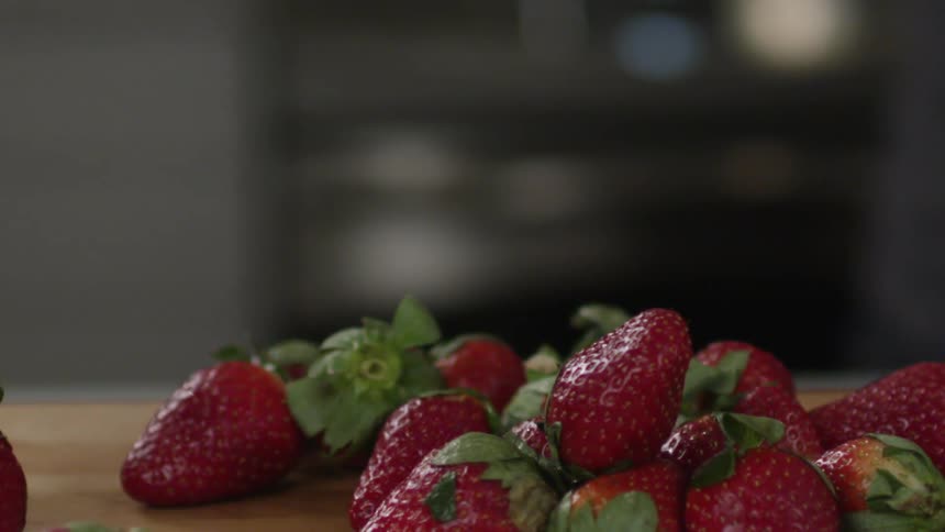 Strawberries are poured from a bowl onto a table