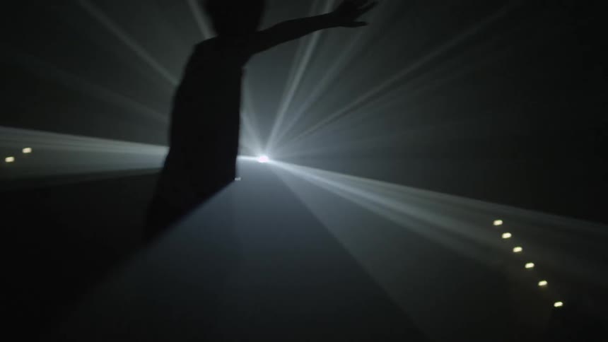 Man stands in front of a strobe light waving his hands
