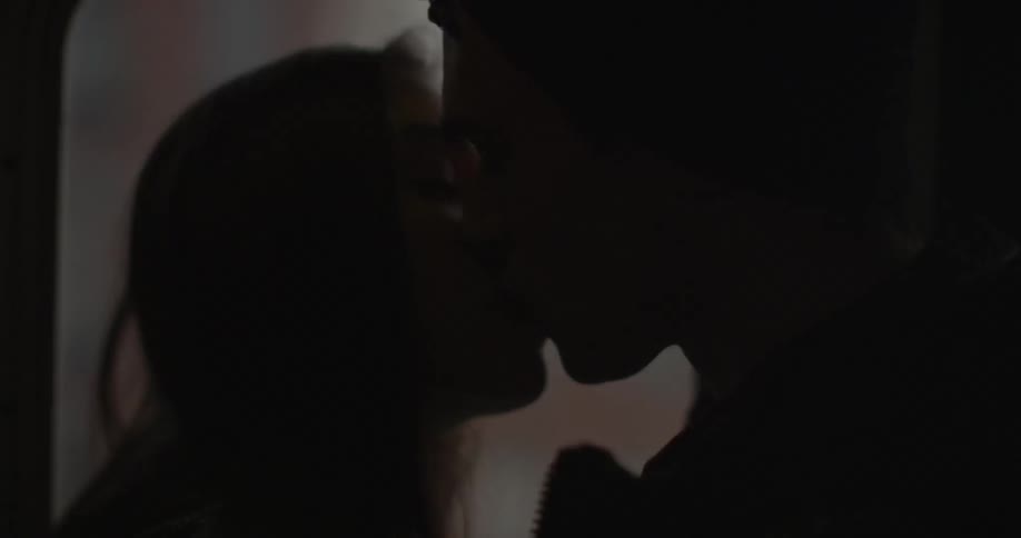 A man and woman kiss on a train