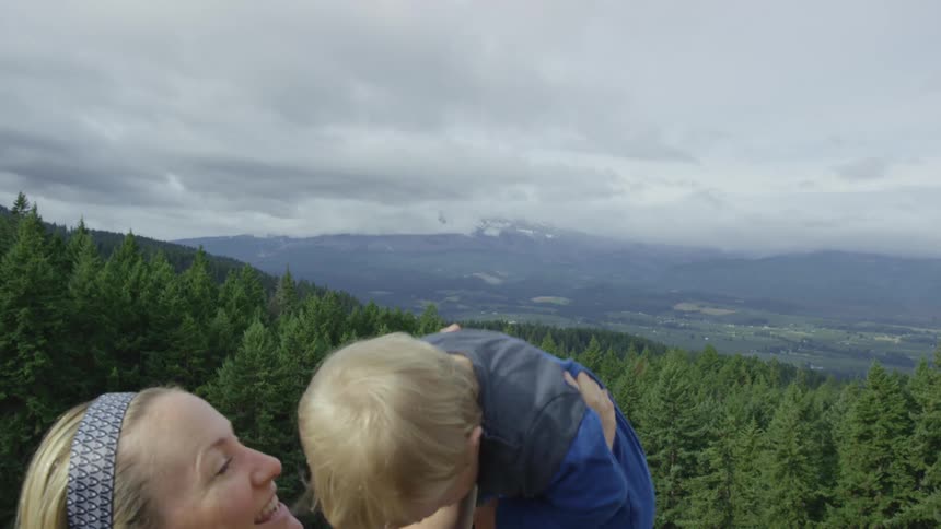 A young mother playfully lifts here baby into air while he giggles and laughs