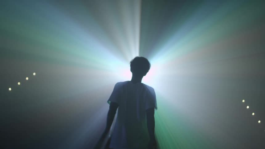 Man waves his arms at a strobe light