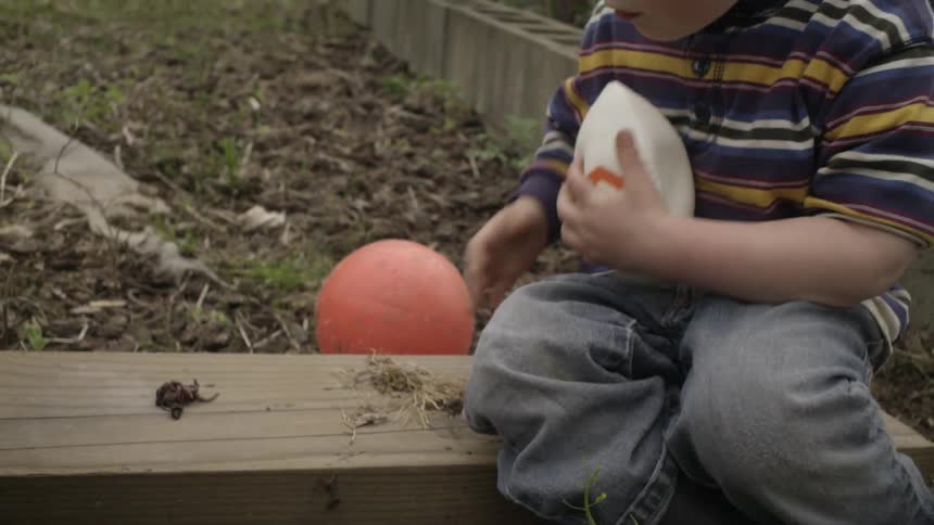 A young boy playing with a small foam ball