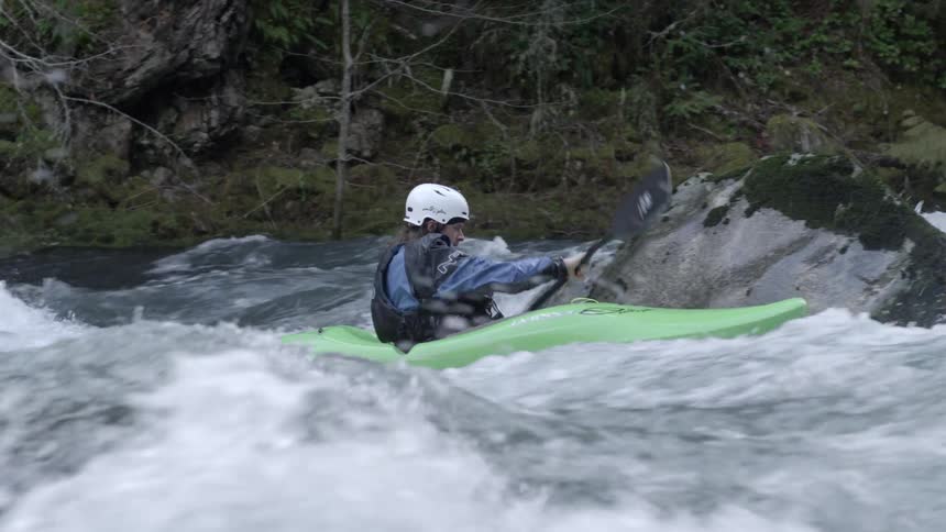 A whitewater kayaker paddles towards camera as he navigates challenging moves in the river