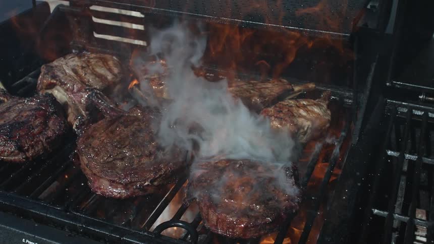Grilling steaks being splashed with liquid